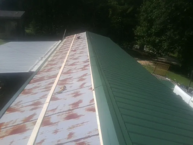 Old rusted panels beside newly installed green metal roofing — Wind Damage Roof Repair by Roofing Brothers in Gloucester