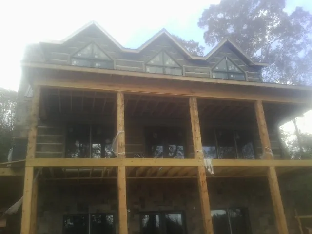 Dormers and porch framing on a large log home under construction — Roof Coating work by our crew in Gloucester