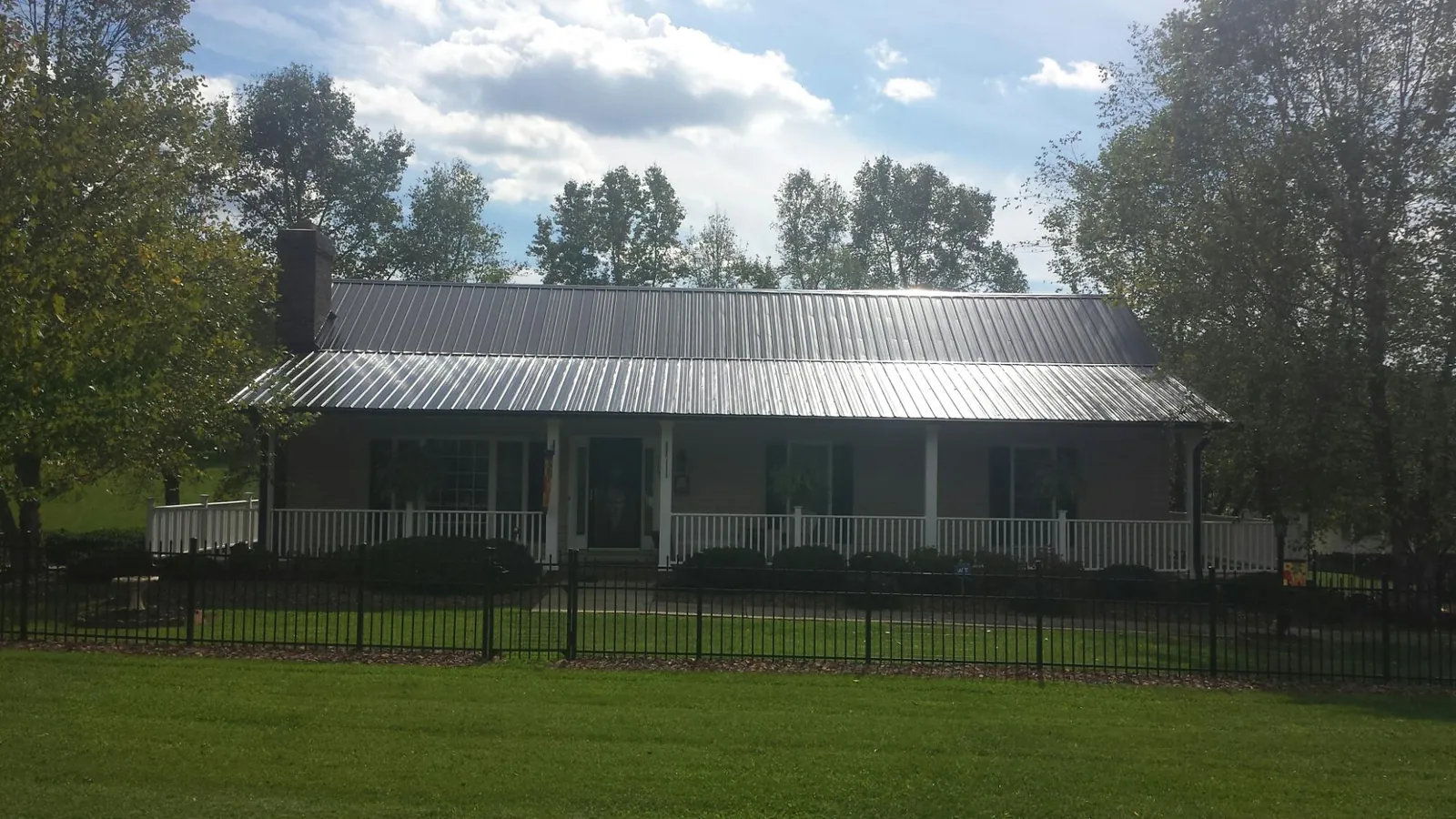 Gray metal roof on a brick ranch with a full width front porch — Gutter Guard Installation work by our crew in Gloucester